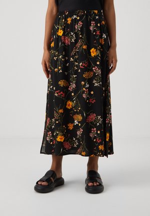 Czarna spódnica midi z elastycznym pasem, ozdobiona pomarańczowymi, różowymi i białymi kwiatowymi wzorami, noszona z czarnymi sandałami typu slide.