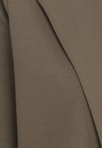 Tissu marron à la texture douce, présentant un pli diagonal. Fini lisse et mat ; aucun motif ou accessoire visible.