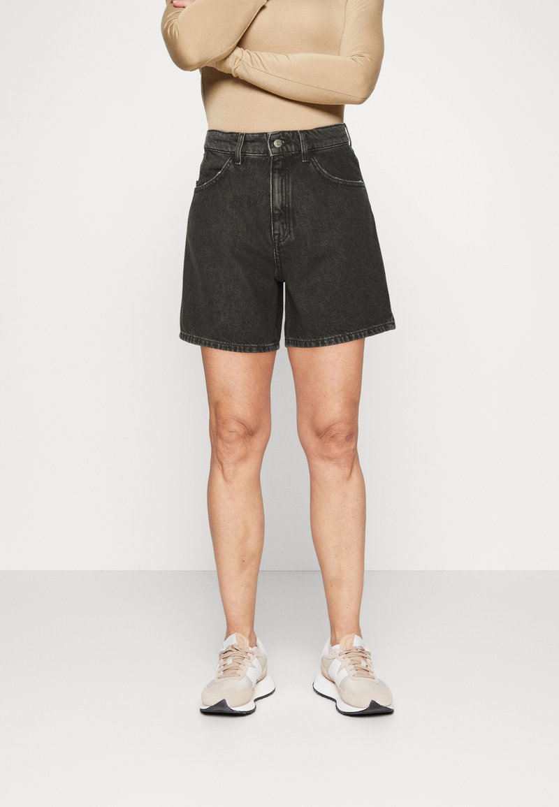Svarta denimshorts med hög midja, utrustade med bältesöglor, två framfickor och rak ben-design. Och tillsammans med ljusa sneakers.