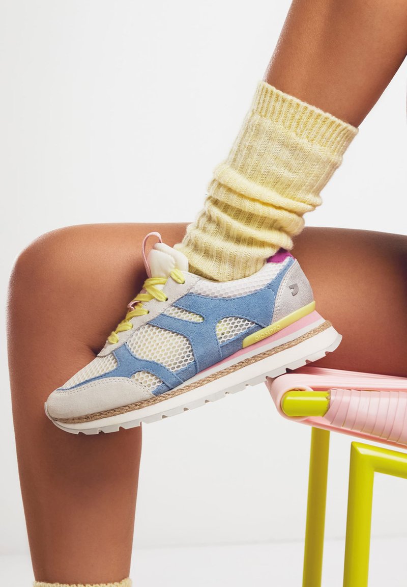 Sneaker sportivo realizzato in mesh e suede, nei colori azzurro chiaro, grigio e bianco, con lacci gialli e un accento rosa sul tallone.