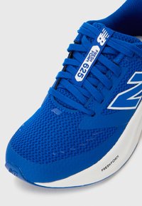 Chaussure de sport bleue avec une tige en maille, des lacets plats, un logo "Fresh Foam" sur le côté et une semelle intermédiaire blanche rembourrée.