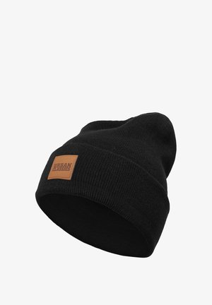 Black knitted beanie with a folded cuff and a square brown leather patch labeled "URBAN CLASSICS." Soft texture, tubular shape.