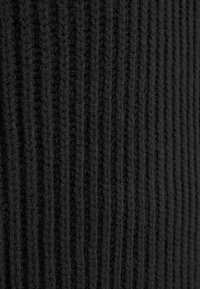 Schwarzer, gerippter Strickstoff mit vertikalen Streifen, einer weichen Textur und einem durchgehend einheitlichen Muster.