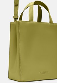Torebka Liebeskind w matowej, limonkowej skórze ekologicznej z podwójnymi uchwytami, odpinanym paskiem oraz wytłoczonym logo marki na dnie.