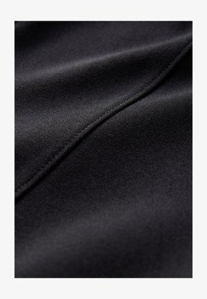 Sort stof med en glat tekstur, der har en subtil glans og buet syningsdetalje. Nærbillede fremhæver materialets blødhed.