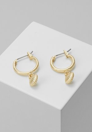 Boucles d'oreilles créoles en or avec petits charms texturés en forme de coquillage, présentées sur une surface blanche inclinée avec des tiges et fermoirs en argent.