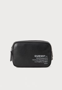 Schwarze, strukturierte Ledertasche mit silbernem Reißverschluss, auf der Vorderseite mit aufgedrucktem weißem Logo und Adressdetails. Kompakte rechteckige Form.