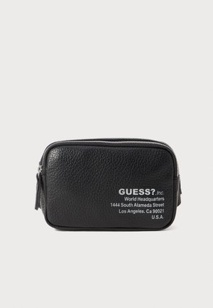Schwarze, strukturierte Ledertasche mit silbernem Reißverschluss, auf der Vorderseite mit aufgedrucktem weißem Logo und Adressdetails. Kompakte rechteckige Form.