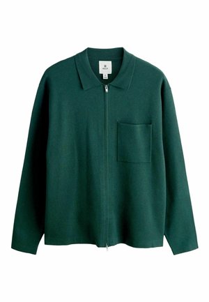 Roheline lukuga jakk, mis on valmistatud pehmest kangast, kaelusega kraega, pikkade varrukatega ja ühe rinnataskuga. Omadusena lõdvestunud istuvus.