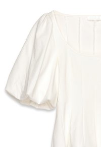 Witte blouse met opgezette mouwen, gemaakt van zachte stof. Heeft een ronde halslijn en verticale naden voor structuur.