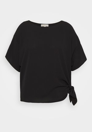 Blouse noire à manches courtes avec un col rond et un détail de nœud latéral à l'ourlet.