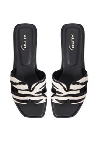 Mules ouvertes en noir et blanc avec des brides en cuir de vache à rayures zèbres, un semelle intérieure rembourrée et une semelle lisse noire. Nom de la marque "ALDO" embossé.