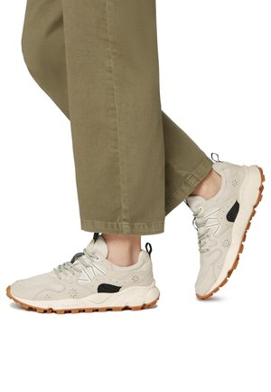 Baskets de sport beige en daim et en mesh, avec une touche de noir, semelle texturée et lacets gris. Semelle en caoutchouc avec un motif de traction.