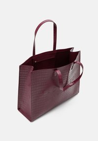 Sac cabas en cuir artificiel effet crocodile couleur bordeaux, avec deux poignées, ouverture supérieure, et une poche intérieure zippée, présentant une texture lisse et une forme structurée.