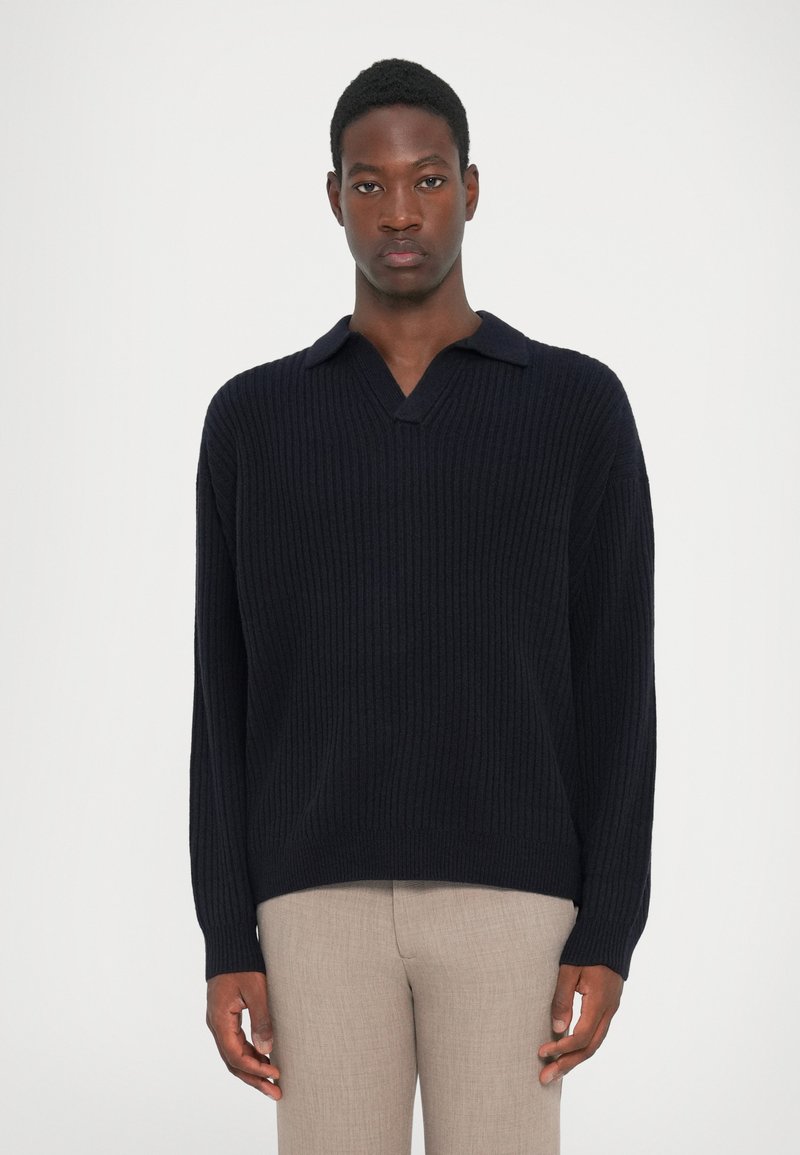 Navy ribbed knit sweater with a V-neck and short collar, featuring long sleeves and a relaxed fit, made of textured material.
