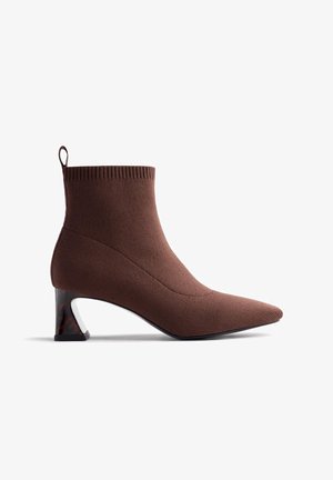 Botte de cheville marron avec une texture en tricot, bout pointu et un talon géométrique unique avec un accent en écaille de tortue.