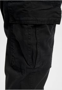 Zwarte cargobroek met een textuurstof, zijzakken en zichtbare stikdetails, met een ontspannen pasvormdesign.