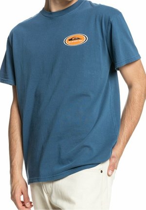 Blauw katoenen T-shirt met een ronde hals, korte mouwen en een rond oranje logo op de linkerborst. Soepele textuur en een ontspannen pasvorm.