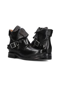 Black leather ankle boots with folded tops, silver buckles, straps, and worn soles visible on white background.