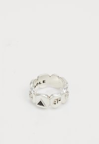 Silver ring with raised geometric shapes including a black triangle and embossed letters on each segment, photographed on a white background.