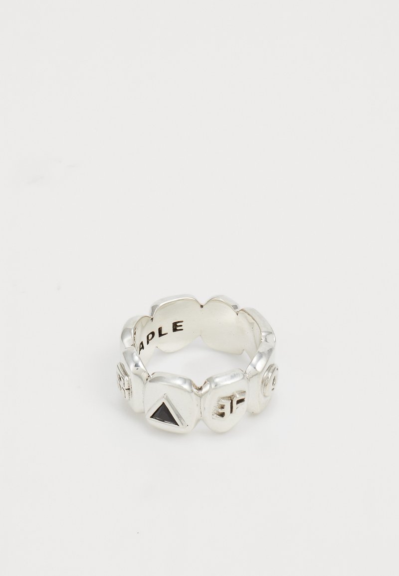 Silver ring with raised geometric shapes including a black triangle and embossed letters on each segment, photographed on a white background.
