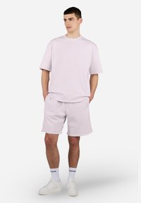 Ensemble t-shirt et shorts en coton rose clair. Le t-shirt a un col rond et des manches courtes, tandis que les shorts disposent d'une taille élastique.