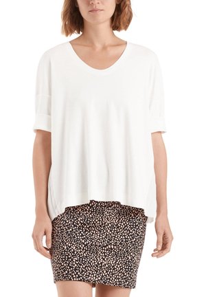 Biała bluzka z krótkim rękawem i dekoltem w szpic o luźnym kroju, zestawiona z czarną spódnicą ozdobioną różowym kropkowanym wzorem. Miękki materiał, casualowy design.