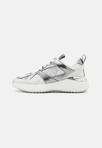 Hvit og sølv atletisk sneaker med overdel av mesh og syntetisk materiale, med en metallisk glans, snøring og en teksturert gummisåle.