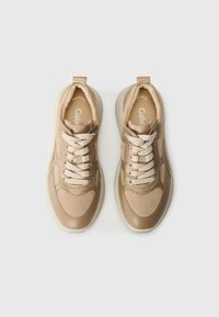 Baskets beige clair avec une finition lisse et texturée, présentant un design à lacets, de subtils accents dorés et une semelle rembourrée.