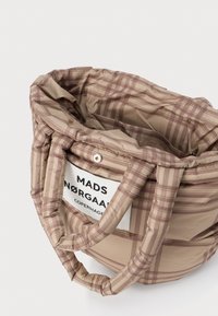 Beige kockás táska párnázott fogantyúkkal és bélés belső résszel. Oldalán látható márkajelzés található. Texturált anyag, puha megjelenéssel.