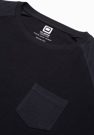 Czarna bawełniana koszulka z teksturowanym, ryflowanym materiałem. Posiada okrągły dekolt i małą kieszonkę po lewej stronie. Rozmiar: M.