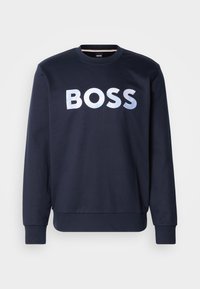 Jūras spēku svīteris, kas izgatavots no mīksta auduma, ar lielu, metālisku sudraba "BOSS" logo priekšpusē. Klasiska apaļa kakla izgriezuma forma un ribbed aproces.
