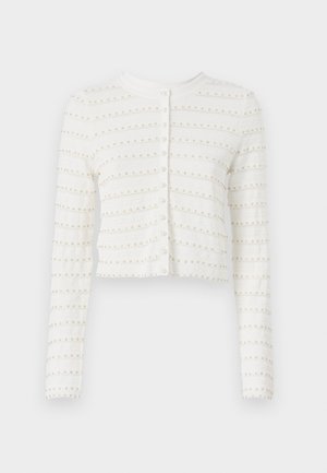 Biała kardigan z długim rękawem o skróconym kroju, z poziomymi teksturowanymi paskami i małymi okrągłymi akcentami. Zapięcie na guziki z przodu.