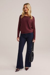 Bordo raukšlėtas megztinis su laisvu pjaustymu, derinamas su tamsiais platėjančiais džinsais ir smailiais bordo aukštakulniais. Juoda petinė sankabėlė su dirželiu.