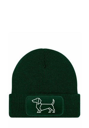 Green knit beanie with a folded cuff, featuring a white outline of a dachshund on a rectangular patch. Textured fabric with ribbed design.