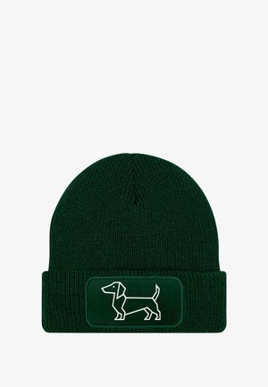 Green knit beanie with a folded cuff, featuring a white outline of a dachshund on a rectangular patch. Textured fabric with ribbed design.