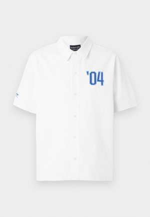 White short-sleeve button-up shirt with collar, blue ’04 text on left chest, and Red Bull Racing Pepe Jeans label inside collar.