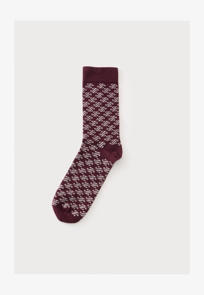 Une chaussette bordeaux unique avec un motif zigzag diagonal blanc et un bord-côtes sur un fond clair uni.