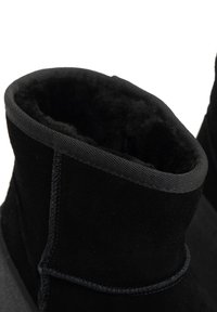 Melnas zamšādas potītes zābaki ar mīkstu iekšējo oderi. Iezīmējas ar gludu virsmu, noapaļu augšu un izturīgu šuvumu gar malām.