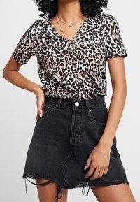 Halenka s leopardím vzorem, krátký rukáv, v hnědé a černé barvě, v kombinaci s černou denimovou minisukní s třepením na spodním okraji a klasickým pětiokou designem.