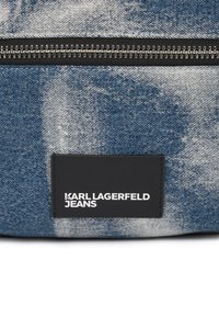 Borsa di jeans con un motivo blu e bianco, una cerniera nera e un'etichetta nera con la scritta "KARL LAGERFELD JEANS" in testo bianco.
