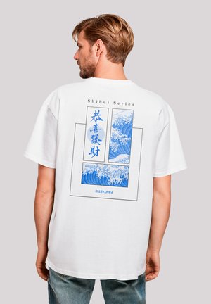 White cotton t-shirt featuring a blue wave graphic on the back, framed by text in black. Loose fit, short sleeves, and round neckline.