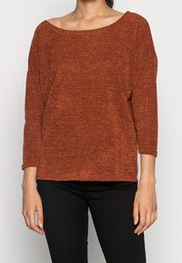 Svetřík rezavé barvy s širokým výstřihem do člunu, tříčtvrtečními rukávy a volným střihem. Texturovaná tkanina s jemným vzorem.