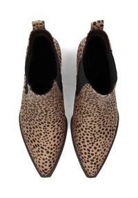 Botines marrones hasta el tobillo con punta afilada, que presentan un patrón de manchas en marrón oscuro sobre un fondo beige. Incluyen paneles laterales elásticos y lengüetas de agarre.