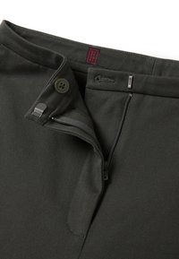 Pantaloni verde oliva con zip e chiusura a bottone, tessuto morbido e etichetta rossa del marchio all'interno della vita.