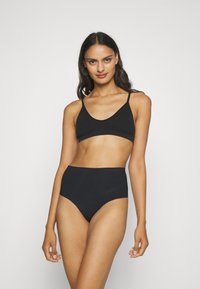 Melna bralette un augsta josta apakšveļas komplekts. Gluda, elastīga auduma ar minimālām šuvēm un regulējamiem ķēdēm. Nav redzamu rakstu vai logo.