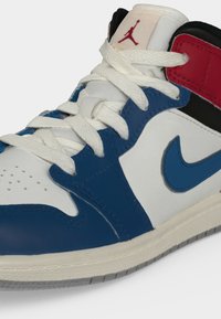 Ψηλό sneaker με λευκά, μπλε, κόκκινα και μαύρα πάνελ, λευκά κορδόνια, το λογότυπο Nike swoosh και το κόκκινο λογότυπο Jumpman στη γλώσσα.