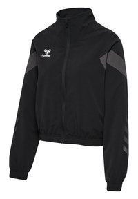 Sort sportsjakke med lynlås, høj krave, elastiske ærme- og bundkanter, grå chevron-detaljer på ærmerne og hvid hummel-logo på brystet.