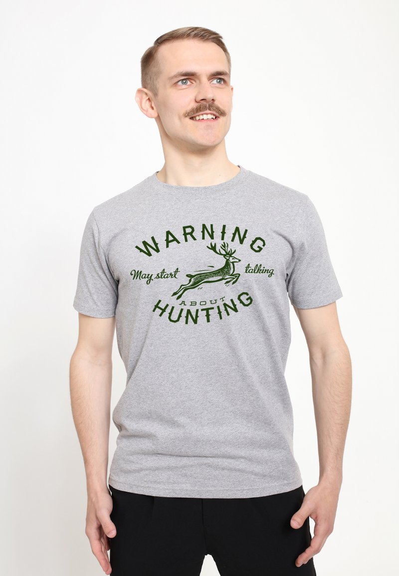 Grå bomulds t-shirt med et grønt grafik med teksten "ADVARSEL, kan begynde at tale om JAGT" og en løbende hjorteillustration.