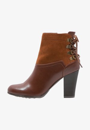 Stivaletto marrone con corpo in pelle e parte superiore in suede, caratterizzato da lacci laterali, un tacco quadrato alto e una finitura liscia e lucida.
